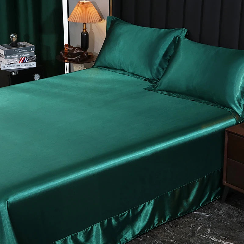 Green satin bedspread and pillows on a bed in a bedroom setting.