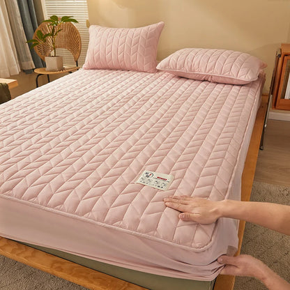 Person adjusting a pink quilted mattress cover on a bed in a bedroom.