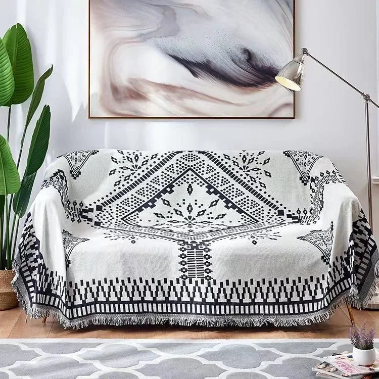 Black and white patterned throw blanket draped over a sofa in a living room.