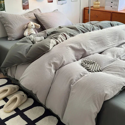 Gray bedding set on a bed with pillows and slippers in a bedroom.