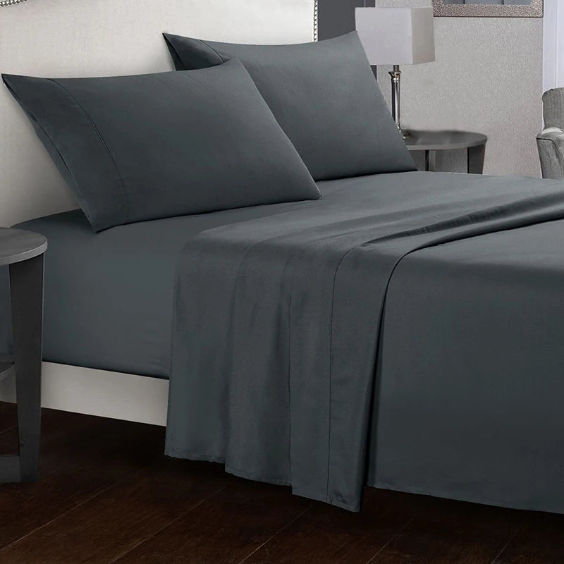 Gray bed sheets and pillows on a bed in a bedroom setting.