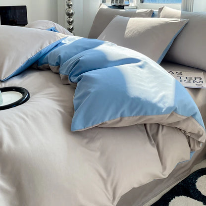 Beige and blue bedding set on a bed with pillows and a blanket.