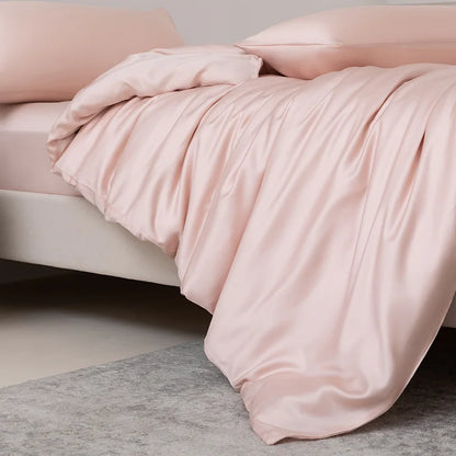 Pink satin comforter on a bed with a neutral background