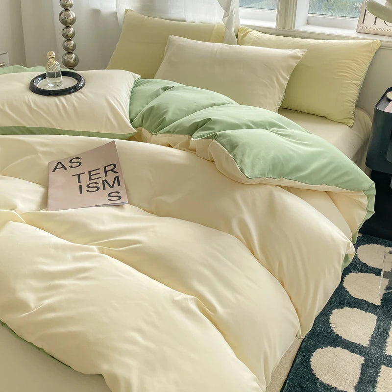 Neatly made bed with green and beige bedding, pillows, and a small pillow with text on a white wall background.