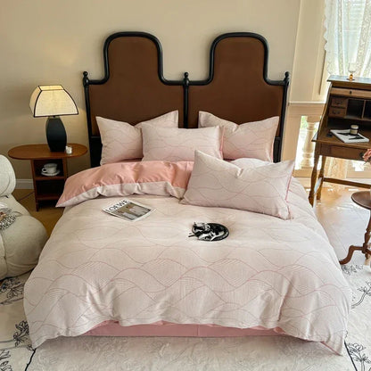 Bedroom with a bed featuring pink bedding and pillows, a lamp on a nightstand, and a desk.