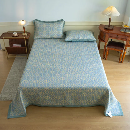 Bed with blue floral patterned cover and pillows in a bedroom setting.