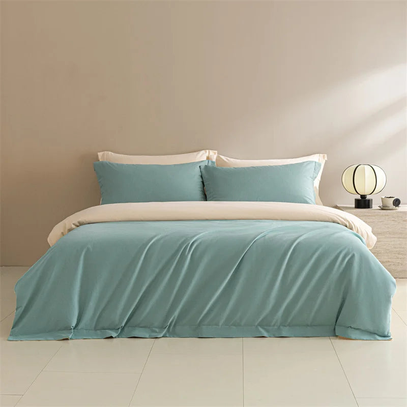 Teal bedspread and pillows on a bed in a minimalistic bedroom setting.