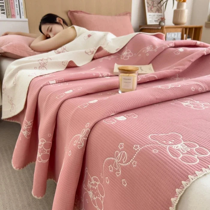 Person lying on a bed with pink floral bedding, next to a small candle.