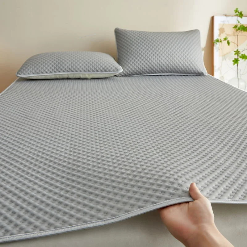 Gray textured mattress cover with pillows on a bed in a bedroom setting
