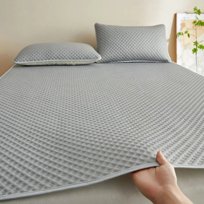 Gray textured mattress cover with pillows on a bed in a bedroom setting