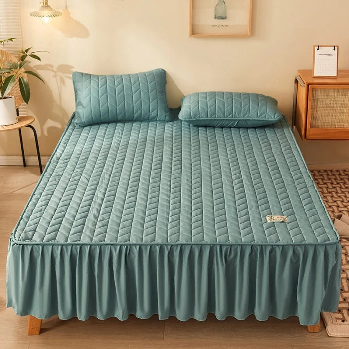 Teal quilted bedspread with matching pillows on a bed in a room setting.