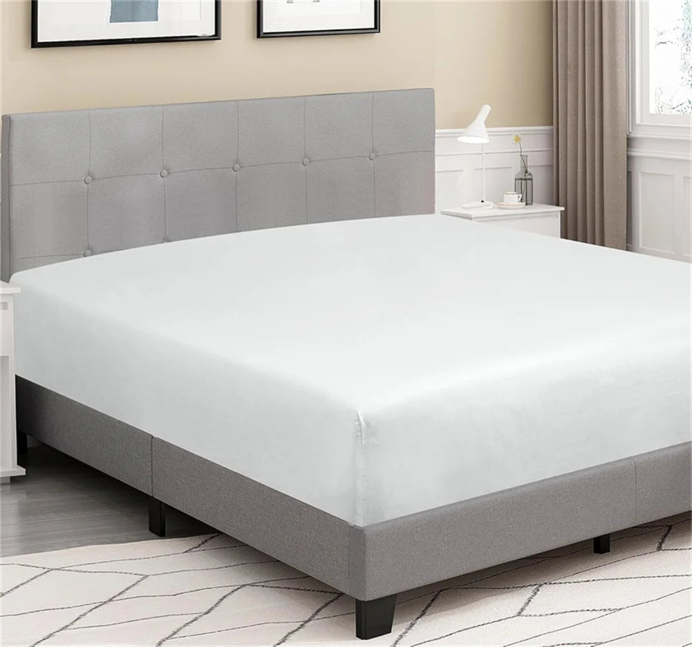 Gray upholstered bed with white mattress in a room with light-colored walls and flooring.