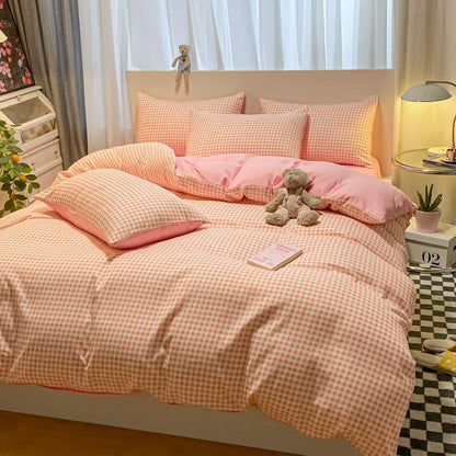 Bedroom with pink checkered bedding and a teddy bear on a bed.