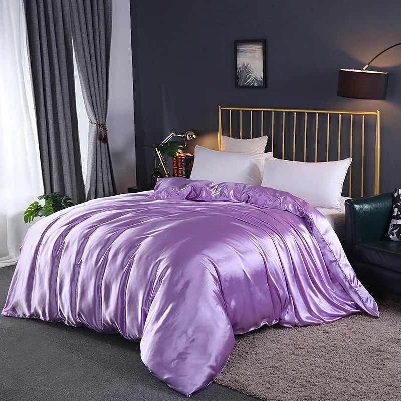 Purple satin comforter on a bed in a bedroom setting with a gold headboard.