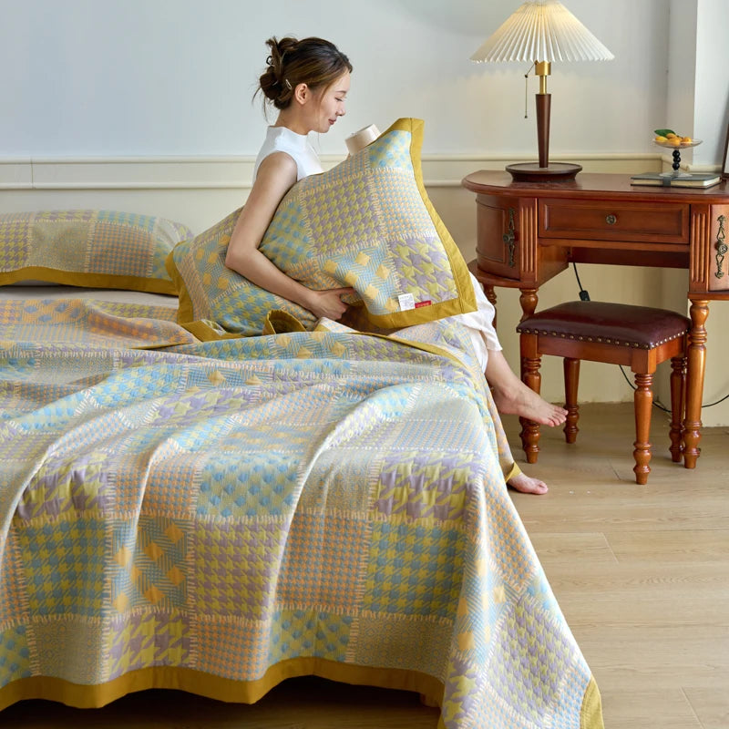 Woman arranging pillows on a bed with a checkered blanket in a bedroom setting.