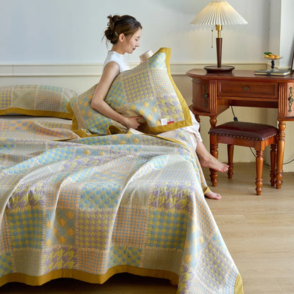 Woman arranging pillows on a bed with a checkered blanket in a bedroom setting.