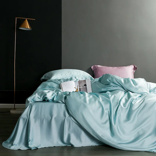 Teal bedding set on a bed with a gray wall and standing lamp in the background