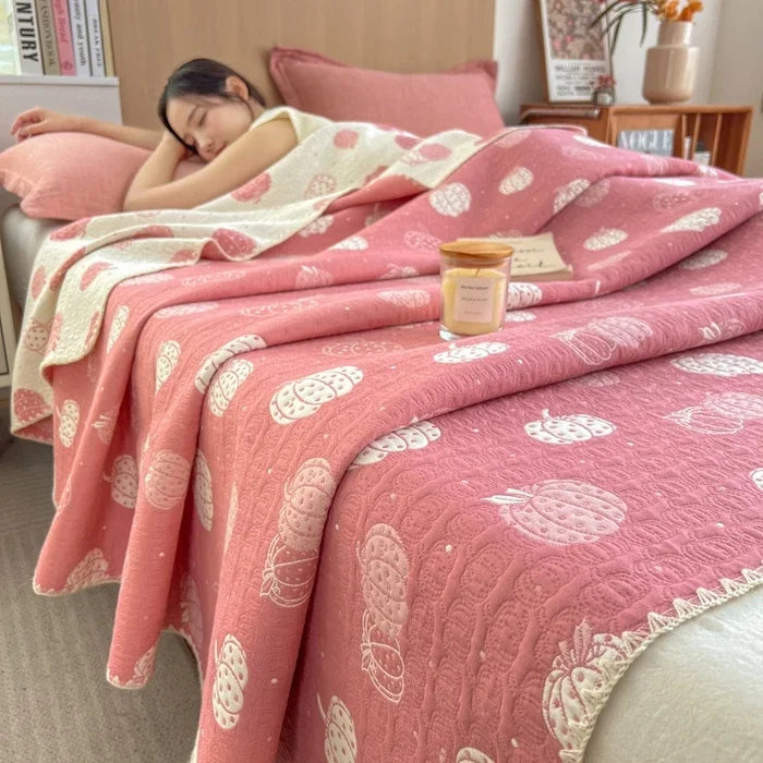Person lying on a bed with pink and white patterned bedding, surrounded by books and decor.