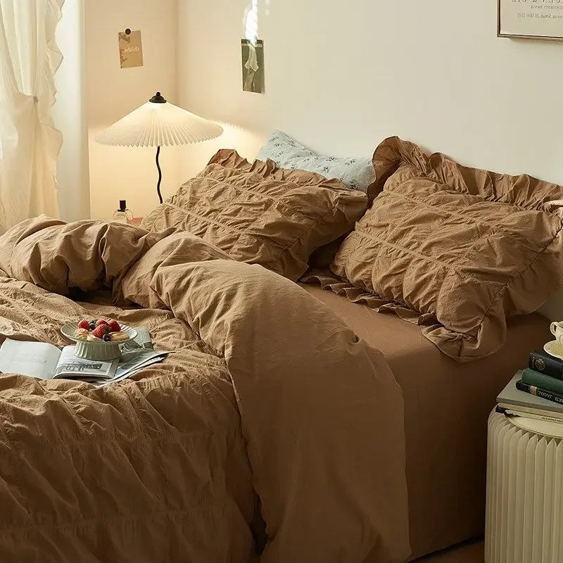 Bedroom with brown bedding, lamp, and books on a nightstand.