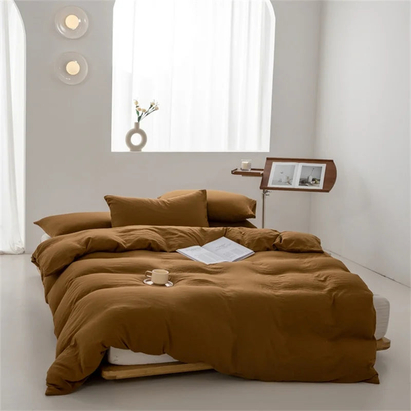Brown Green bedspread on a bed in a minimalistic room with a side table and lamp.