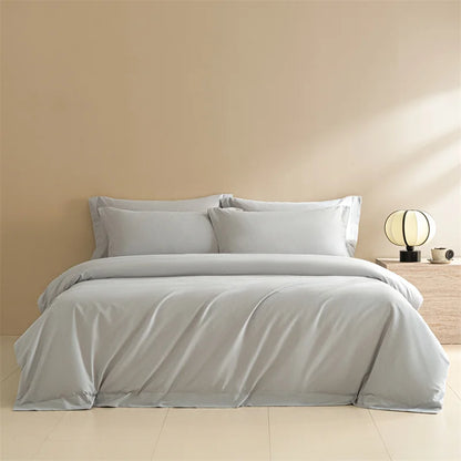 Gray bedding set on a bed in a minimalistic bedroom with a beige wall and wooden nightstand.