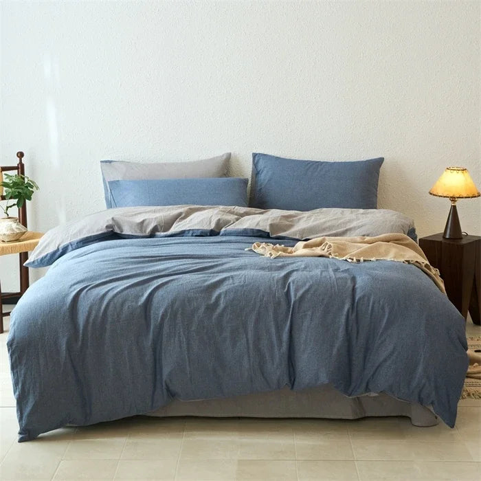 Blue bedding set on a bed in a bedroom with a lamp and plant.