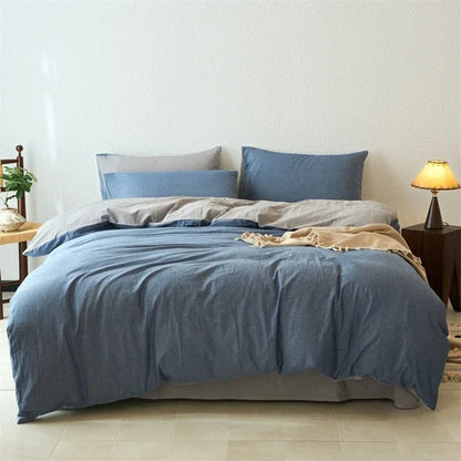 Blue bedding set on a bed in a bedroom with a lamp and plant.