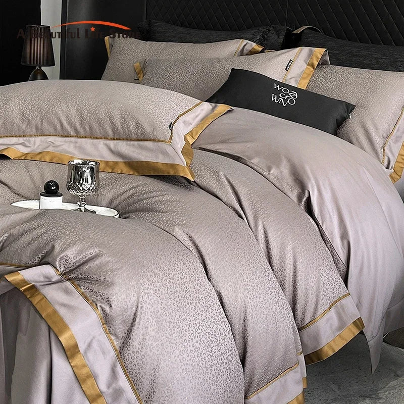 Luxury bed with gray and gold bedding, black lamp, and decorative pillows.