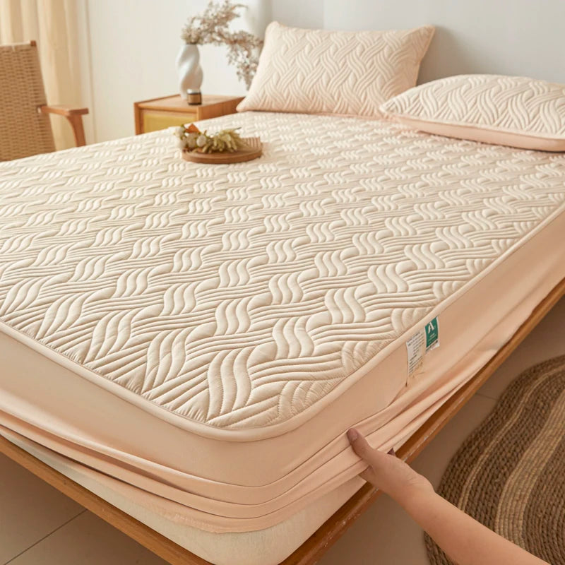 Beige quilted mattress cover on a bed in a bedroom setting