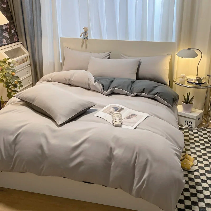 Neatly made bed with gray bedding in a bedroom setting.