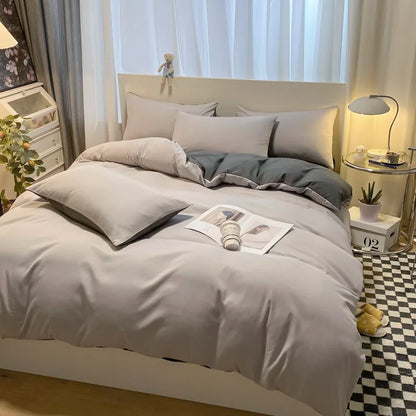 Neatly made bed with gray bedding in a bedroom setting.
