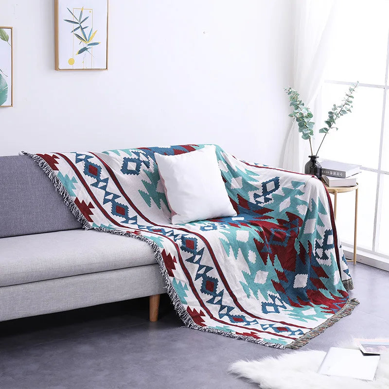Colorful patterned blanket draped over a gray sofa in a living room.