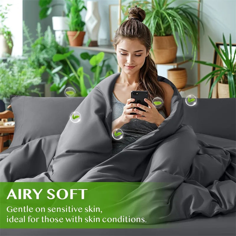 Woman sitting on a couch wrapped in an airy soft blanket with plants in the background