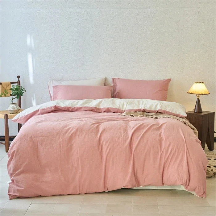 Bed with pink bedding in a room with a lamp and plant.