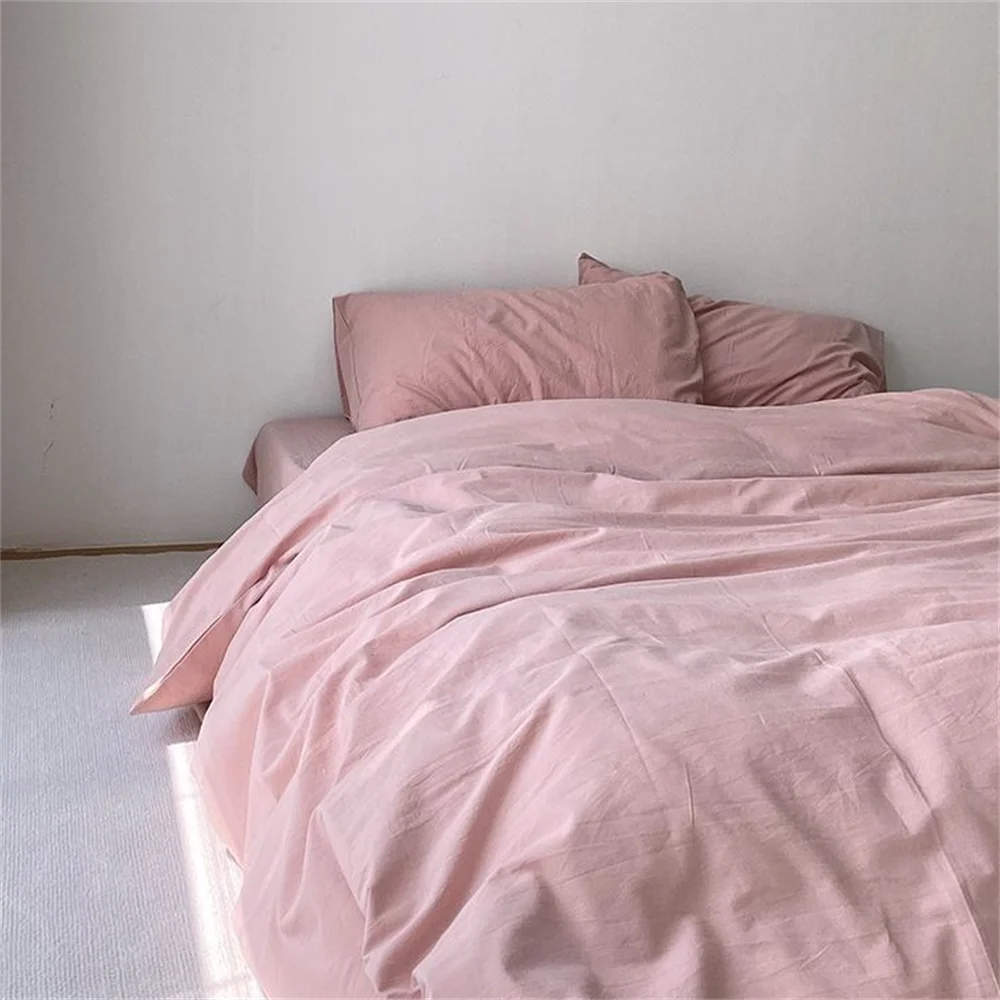 Pink bedding set on a bed against a plain wall