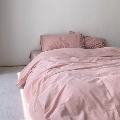 Pink bedding set on a bed against a plain wall