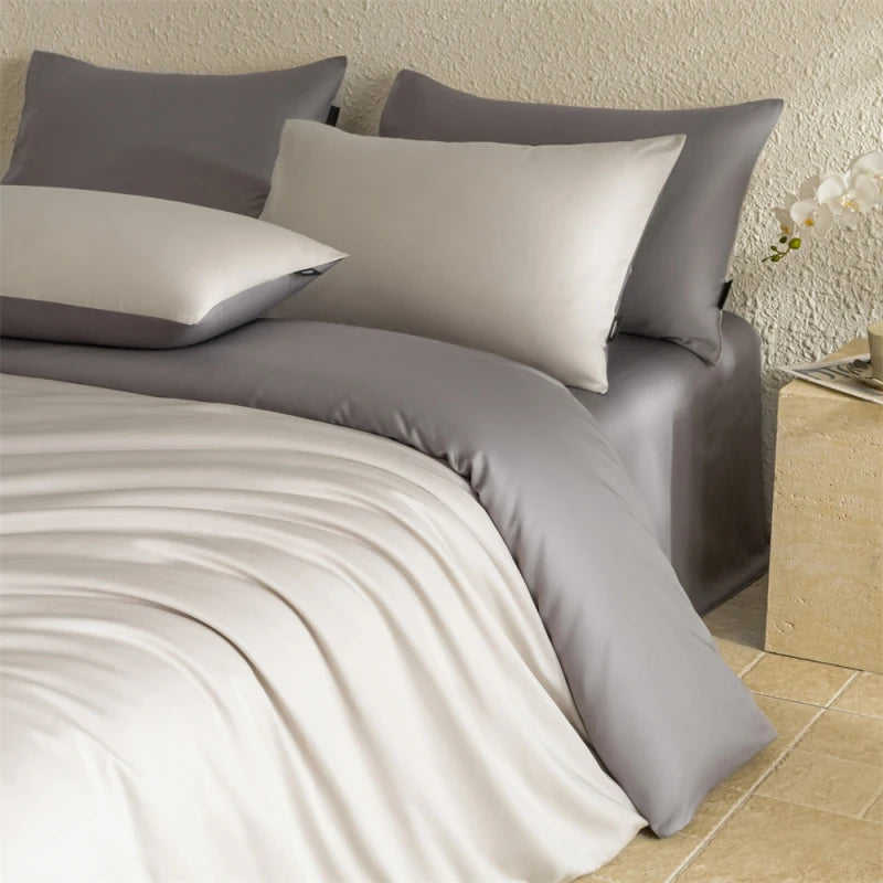 Gray bedding set with pillows on a bed in a bedroom setting.