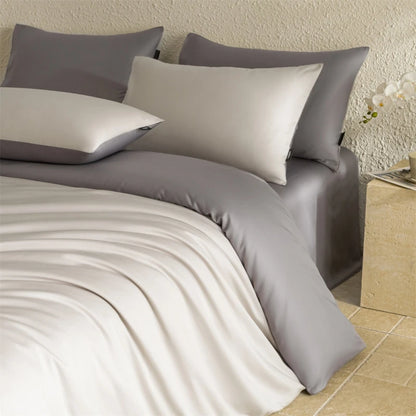 Gray bedding set with pillows on a bed in a bedroom setting.