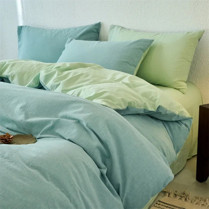 Teal bedding set with pillows on a bed against a white wall.