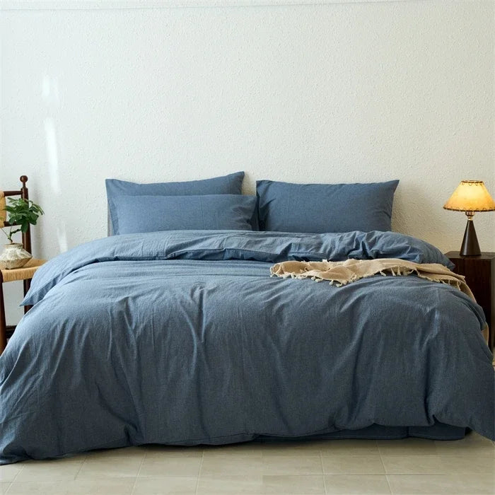Blue bedding set on a bed in a room with a lamp and plant.