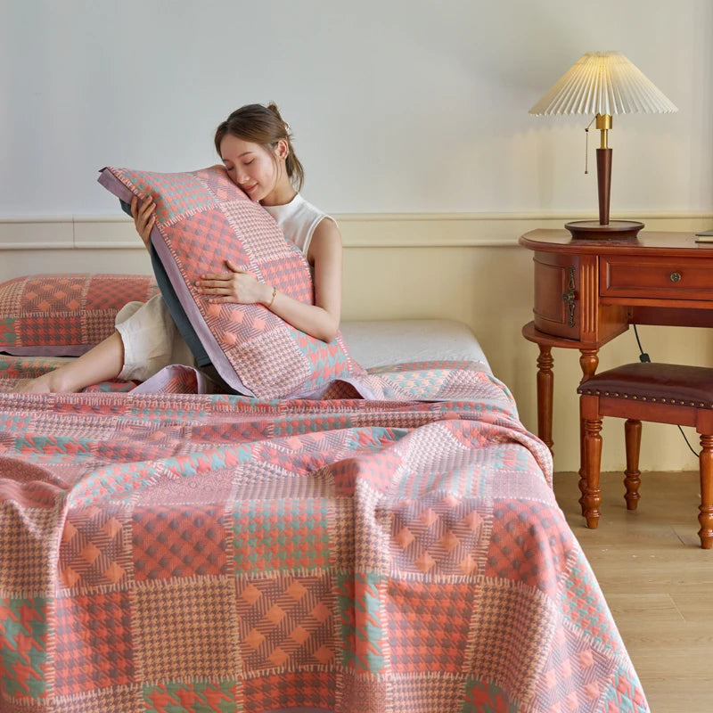 Woman sitting on a bed with a patterned quilt and pillow, in a room with wooden furniture and a lamp.