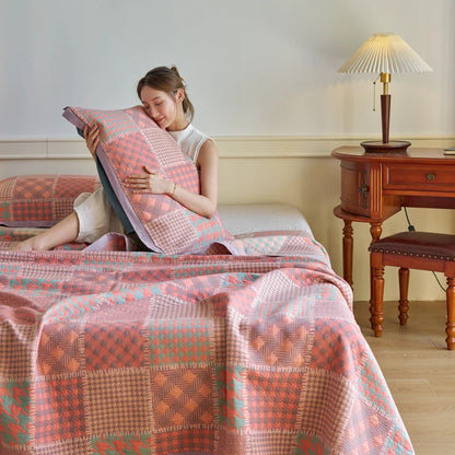 Woman sitting on a bed with a patterned quilt and pillow, in a room with wooden furniture and a lamp.