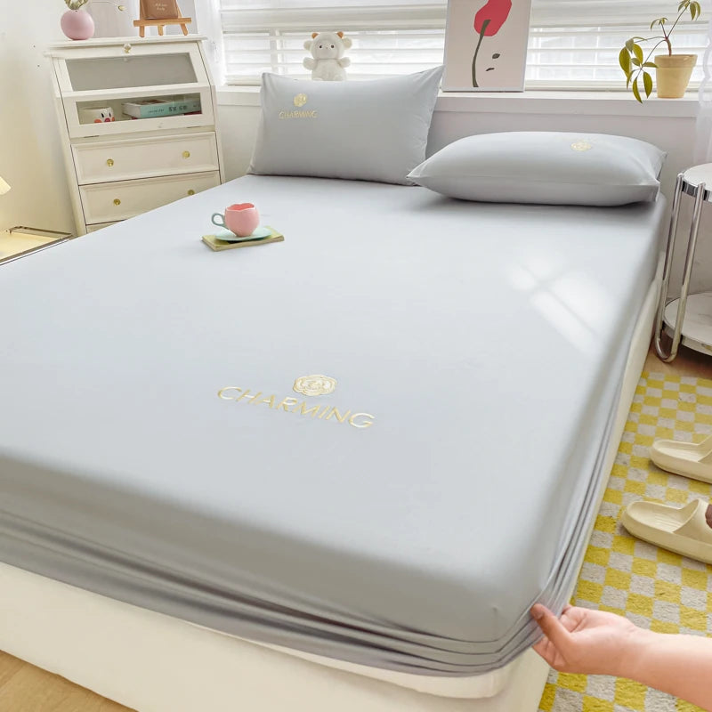 Gray mattress cover on a bed with a visible brand logo in a bedroom setting.