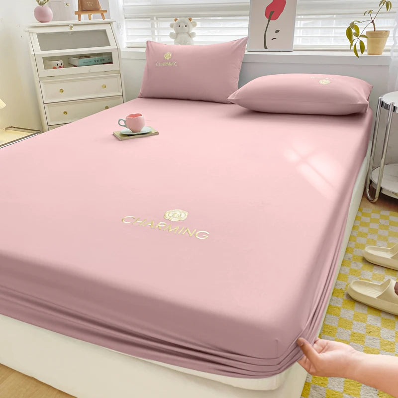 Pink bedsheet with a visible brand logo on a bed in a room setting.