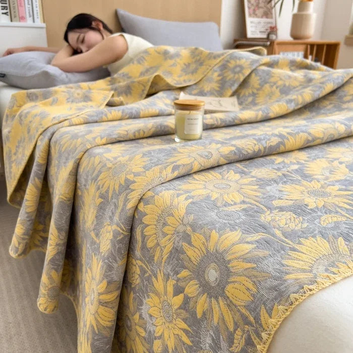 Person lying on a bed with a yellow and gray floral patterned blanket