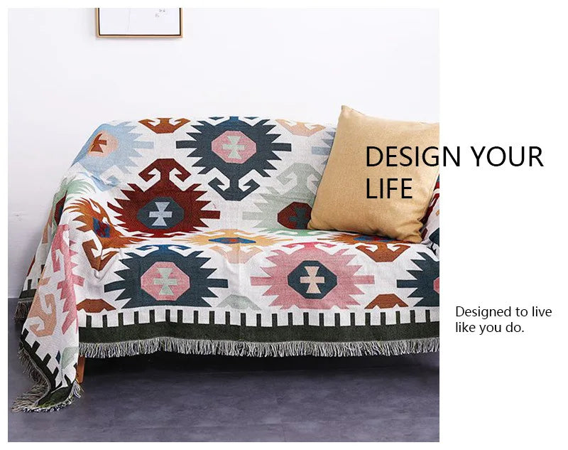 Geometric patterned throw blanket on a couch with 'Design Your Life' text.