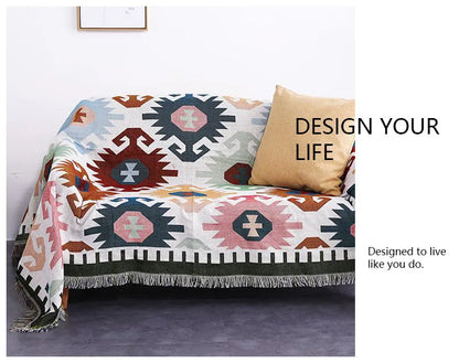 Geometric patterned throw blanket on a couch with 'Design Your Life' text.