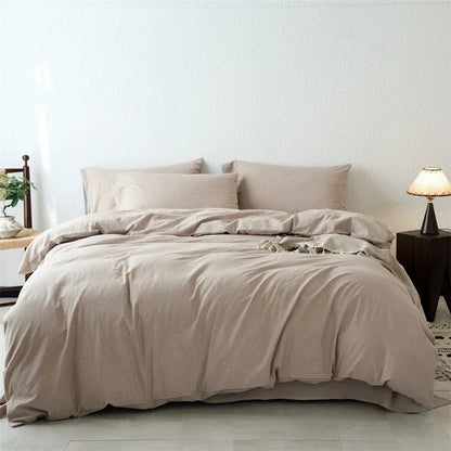 Beige bedding set on a bed in a minimalistic bedroom with a lamp and plant.