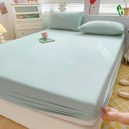 Light blue mattress cover being fitted onto a bed in a bedroom setting.