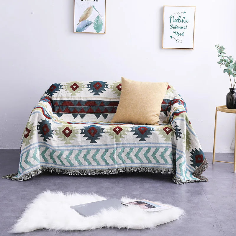 Patterned throw blanket draped over a sofa with a pillow in a room setting.